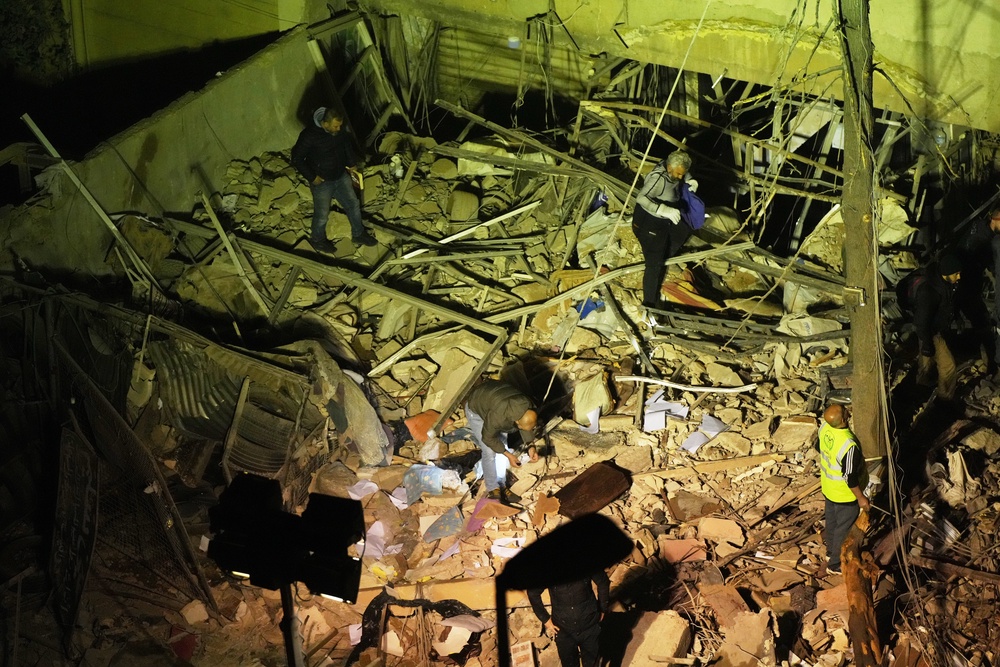 People search through the rubble of a damaged building for survivors following an Israeli airstrike in Dahiyeh, Beirut's southern suburbs (AP)