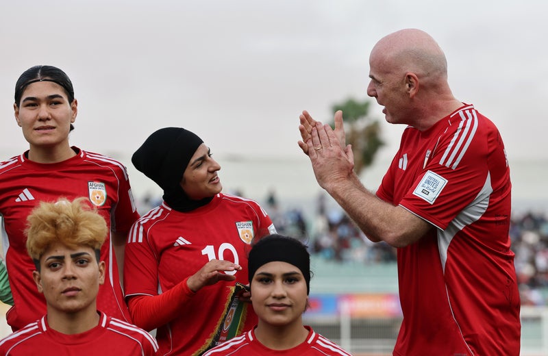 Gianni Infantino, president of Fifa, applauds as he poses for a photograph with players of Afghan Women's United prior to their match against Tunisia on 29 October 2025 (Fifa)