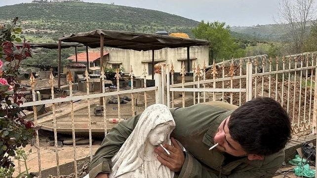 A soldier smokes and pushes another cigarette onto the mouth of a statue of the Virgin Mary in Debel, Lebanon, in this pictur (Reuters)