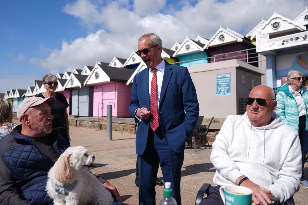 Reform UK leader Nigel Farage talking to a man and his dog after casting his vote in Walton-on-the-Naze (Joe Giddens/PA) (PA Wire)