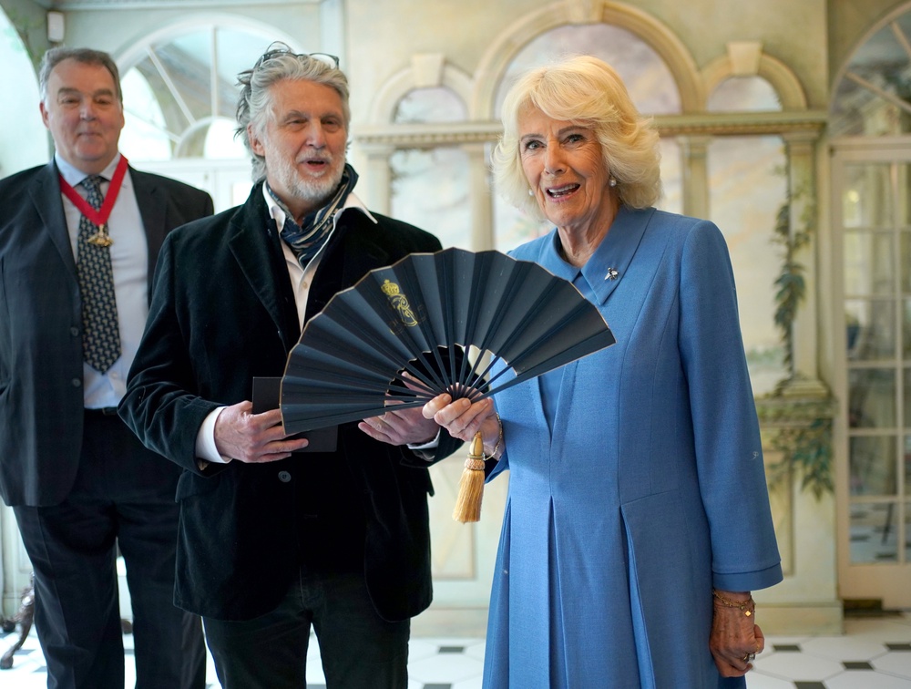 Artist Paul Benney (second left) gives Queen Camilla a fan designed by him (Yui Mok/PA) (PA Wire)