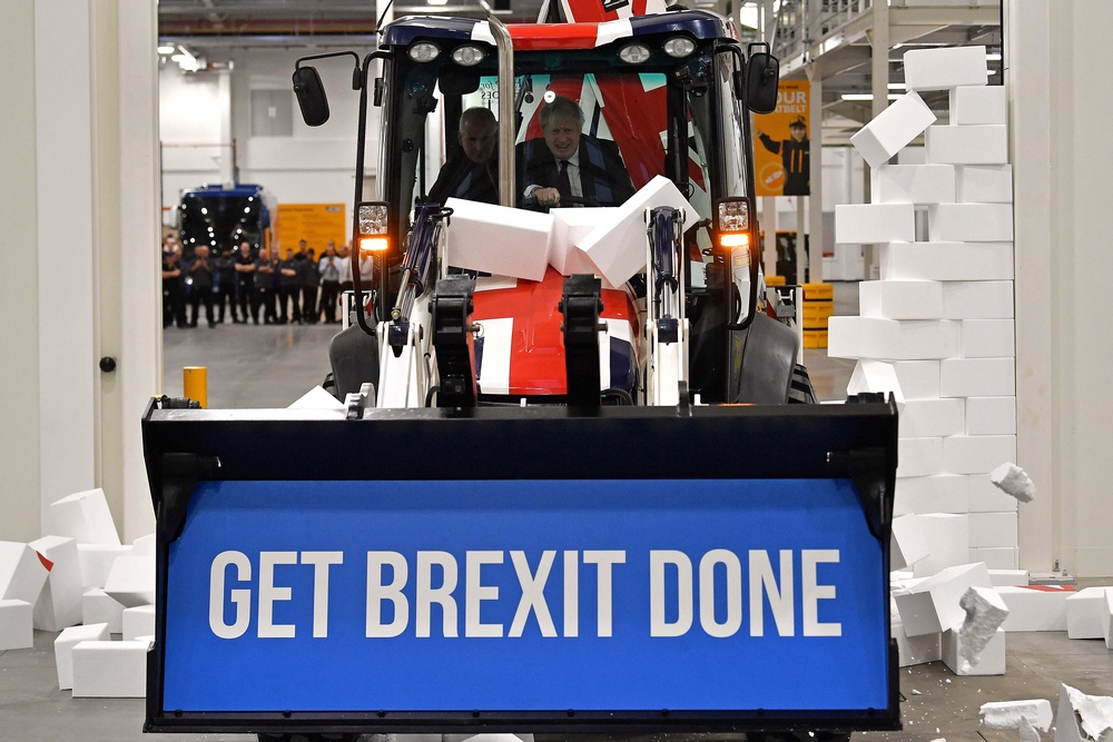 Boris Johnson drives a Union Jack-themed digger through a fake wall (AFP/Getty)