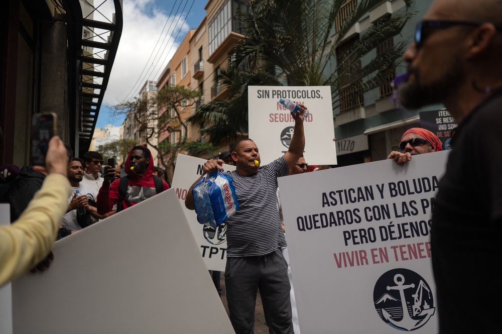 Dockers hold banners reading 'Without protocol, no safety' as they protest against the arrival of a cruise ship affected by hantavirus (AFP/Getty)