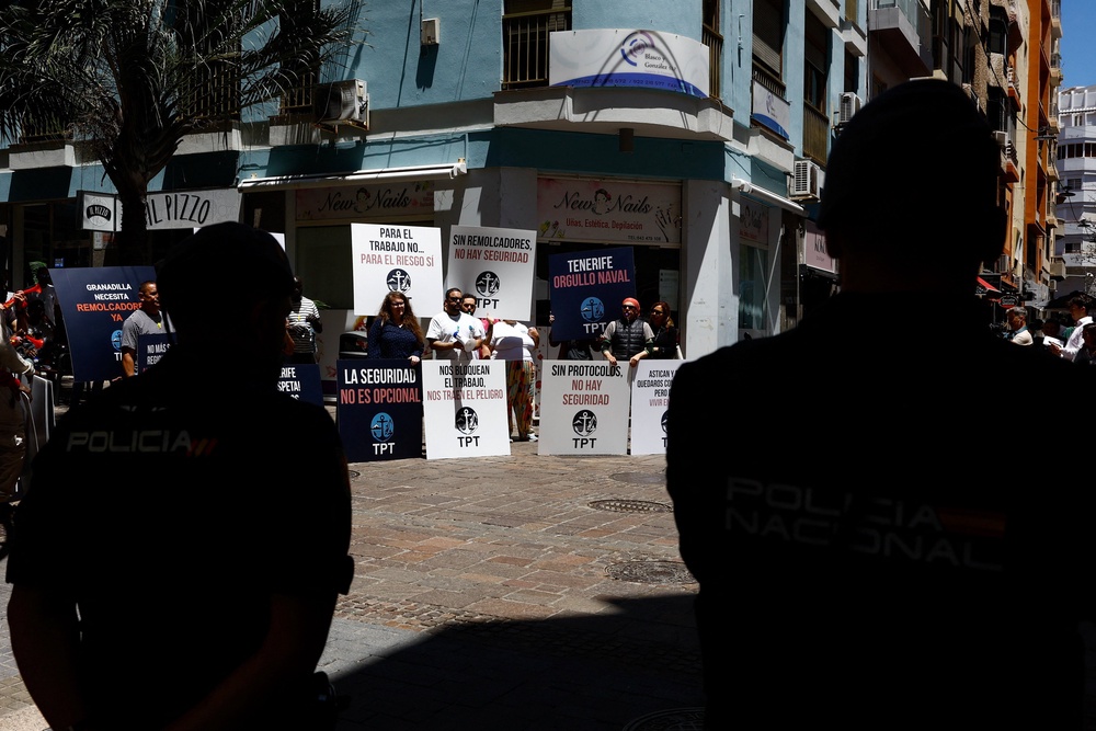 Police officers stand guard as demonstrators with placards attend a protest by port workers over lack of information ahead of the arrival of the MV Hondius (Reuters)
