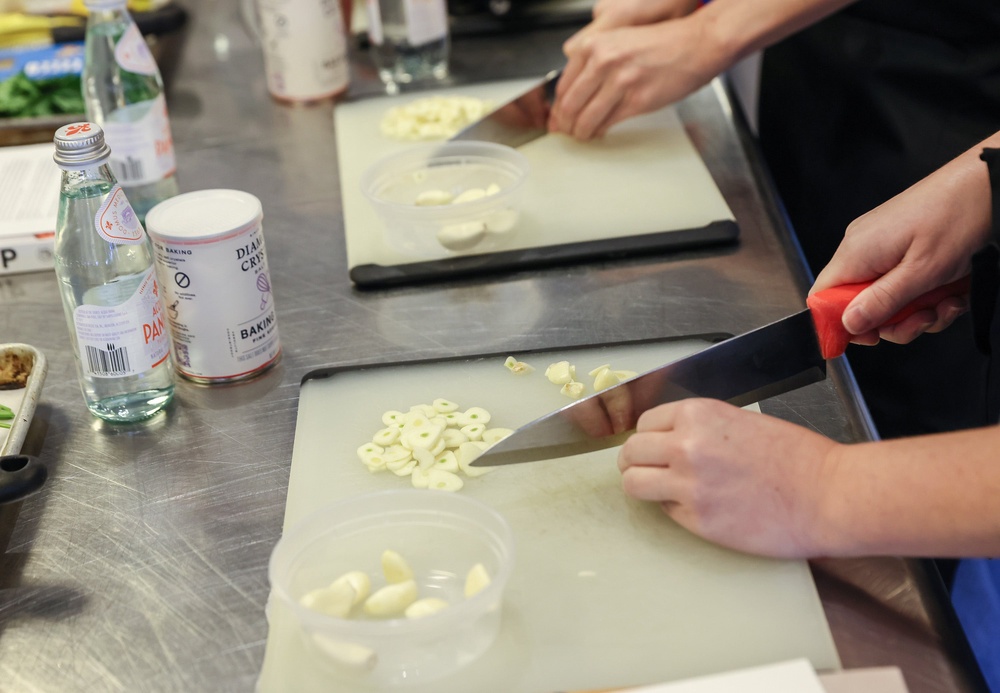 Students chop garlic as they prepare a pasta dish (Getty)