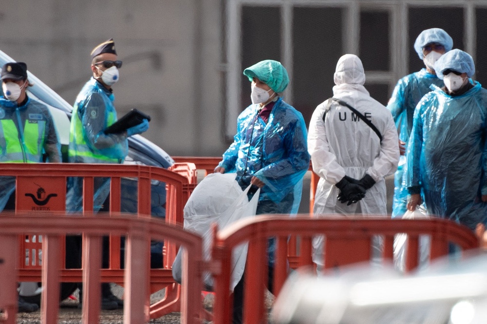 Passengers wearing blue protective suits board a military bus (AFP/Getty)