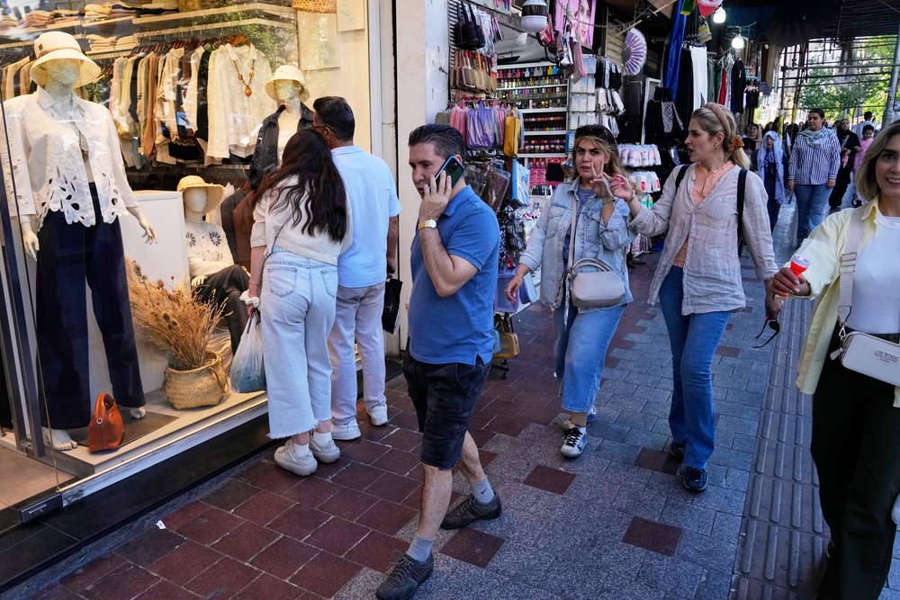 People walk along a sidewalk in northern Tehran, Iran, Sunday (AP)