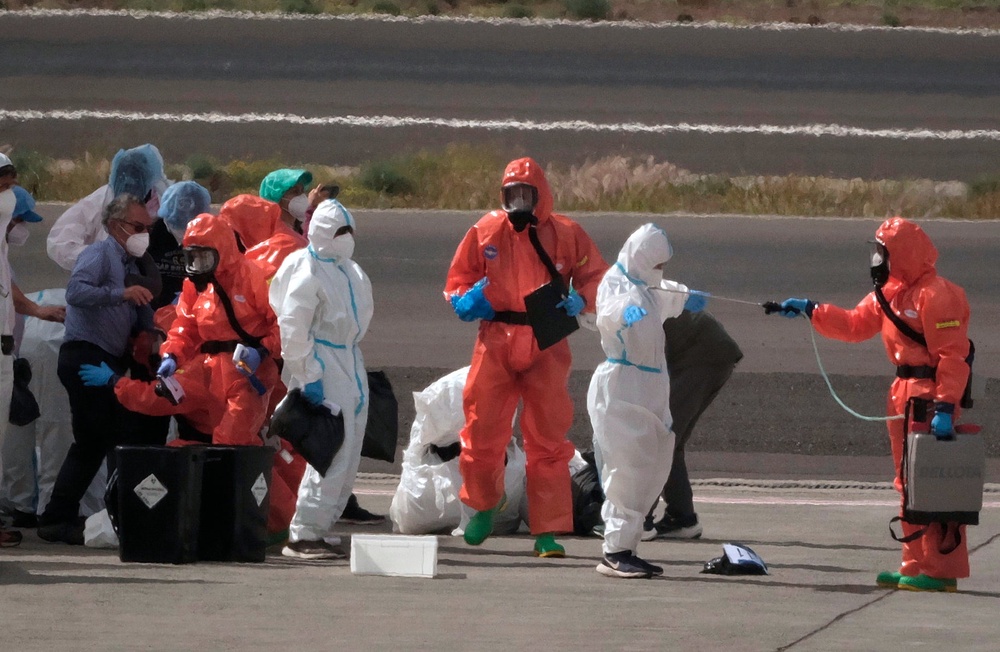 Passengers are sprayed with disinfectant by Spanish government officials before boarding a plane after disembarking from the hantavirus-stricken cruise ship MV Hondius at Tenerife airport (AP/Arturo Rodriguez) (AP)