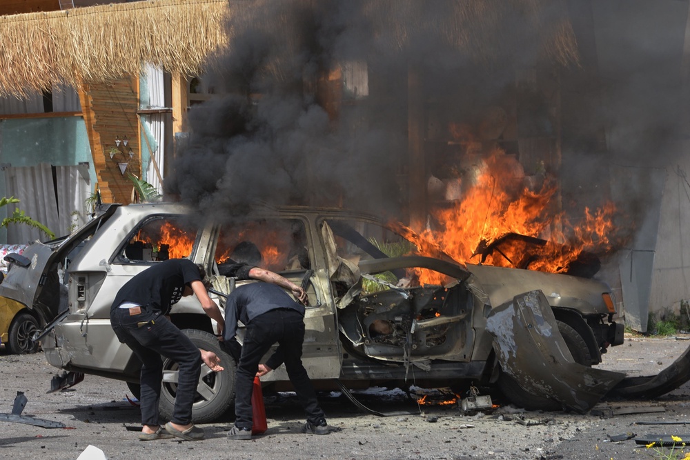 A person is seen inside a burning vehicle as men attempt to put out the fire after an Israeli airstrike hit a car in the coastal town of Barja (AP)