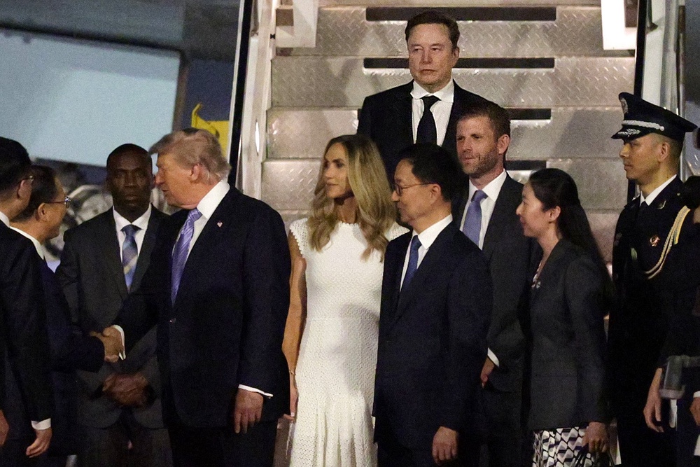 SpaceX CEO Elon Musk, Eric Trump and Lara Trump depart Air Force One as U.S. President Donald Trump greets a local official (Getty)