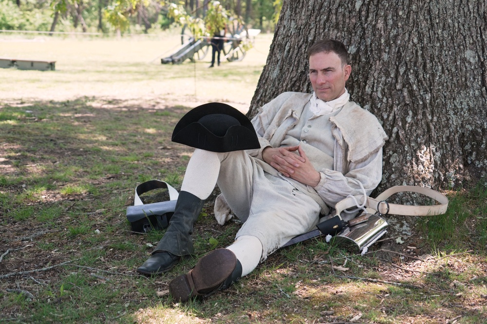 Army officer Jason Monhollen rests beneath a tree during a Revolutionary War event, in which he portrays a private in the 2nd North Carolina Infantry Regiment, in Halifax, N.C., on April 11, 2026. (AP Photo/Allen G. Breed) (Copyright 2026 The Associated Press. All rights reserved)