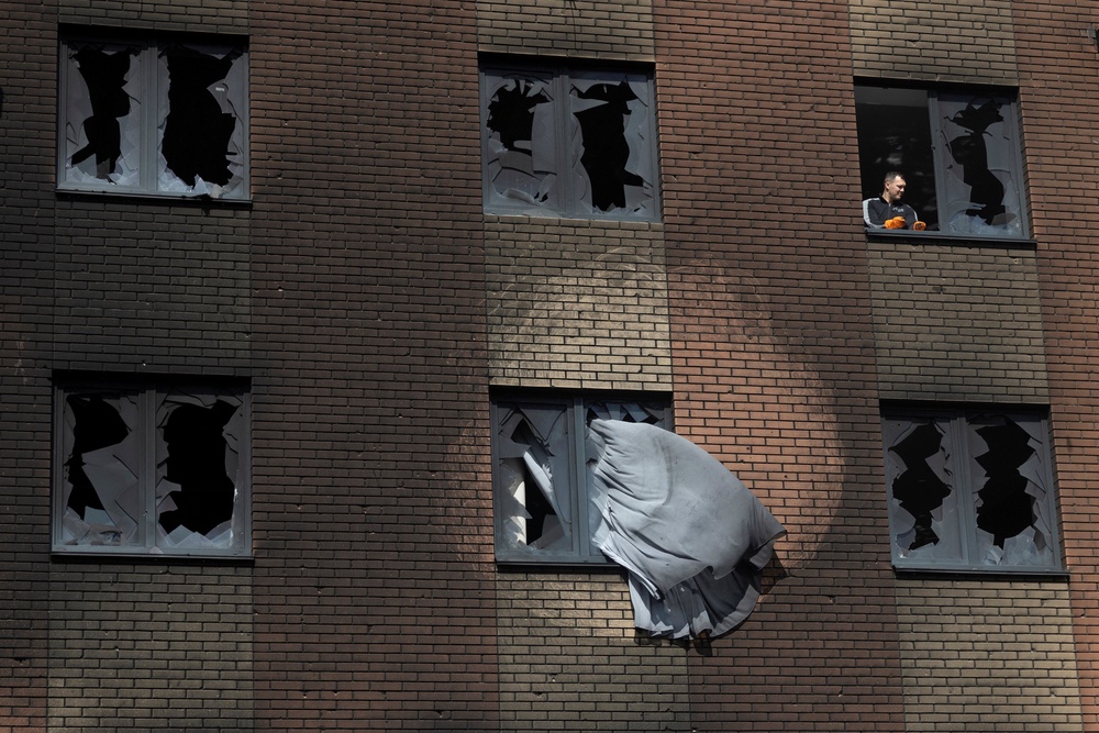 A man clears broken glass at an apartment building that was damaged during a night of Russian missile and drone strikes in Kyiv region (Reuters)
