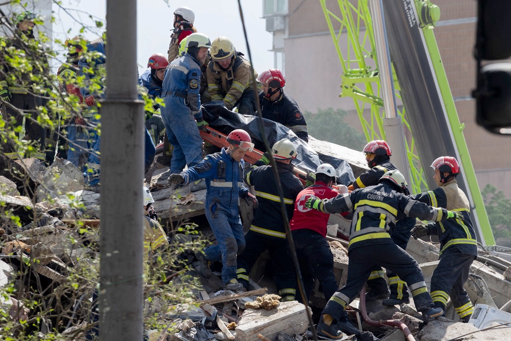 Rescuers carry a body at a partially destroyed residential building following Russian drone and missile strikes in Kyiv on May 14, (AFP/Getty)