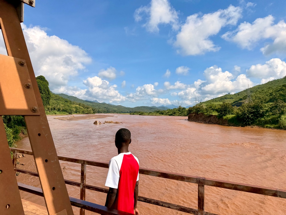 A man crosses the main road bridge across Mkondoa River, the main one in Ulaya, where broken banks and collapsed trees show the damage extreme rainfall has recently caused (Nick Ferris)