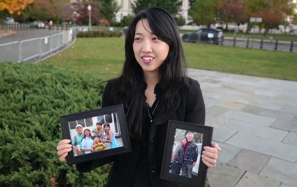 Grace Jin Drexel, 31, daughter of Jin Mingri, olds up two framed photos, one of her father, mother and brothers, and another of her parents (AFP/Getty)