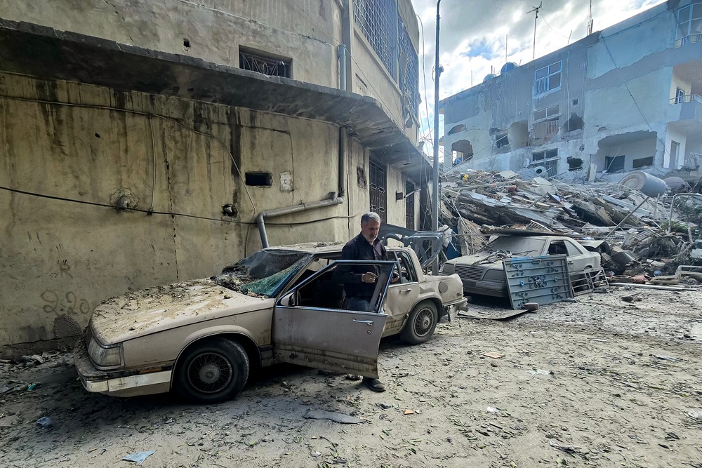 A man stands by the door of a heavily-damaged vehicle by debris and rubble from a collapsed building following overnight Israeli bombardment on Lebanon's southern city of Tyre on May 16, 2026 (AFP via Getty Images)
