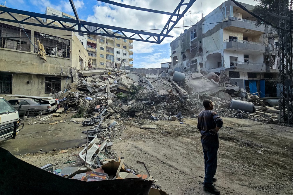 People stand by rubble and debris near damaged and collapsed buildings following overnight Israeli bombardment on Lebanon's southern city of Tyre on May 16, 2026 (AFP via Getty Images)