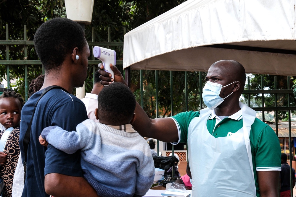 A health official uses a thermometer to screen people in front of Kibuli Muslim Hospital in Kampala, Uganda (AP)
