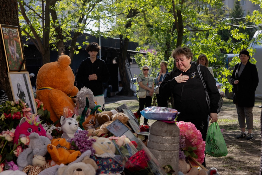 Local residents stand in front of a makeshift memorial near a partially destroyed residential building in Kyiv (AFP via Getty Images)