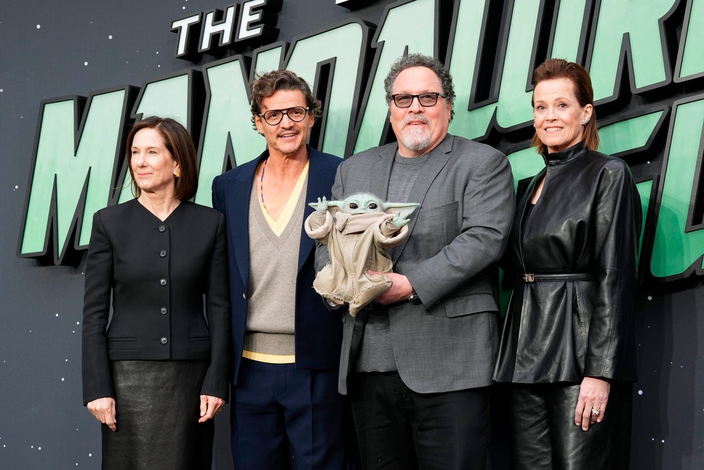 Kathleen Kennedy, Pedro Pascal, Director Jon Favreau, holding Grogu, and Sigourney Weaver attend a fan event for 'The Mandalorian and Grogu' in London (AP)