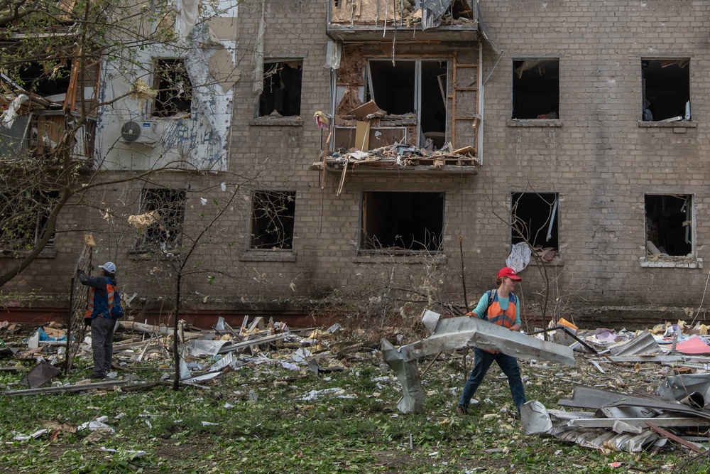 Communal workers clean debris in the courtyard of a damaged residential building following an air attack in Dnipro on May 18 (AFP/Getty)