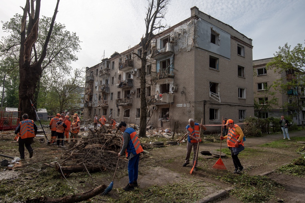 Municipal workers clean debris in the courtyard of a damaged residential building following an air attack in Dnipro on May 18 (AFP/Getty)