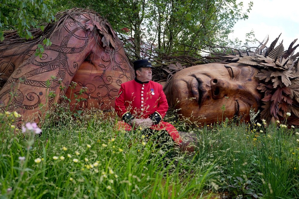 A Chelsea Pensioner sits in the Campaign to Protect Rural England garden at the show, centring on the giant Gaia figure (AP)