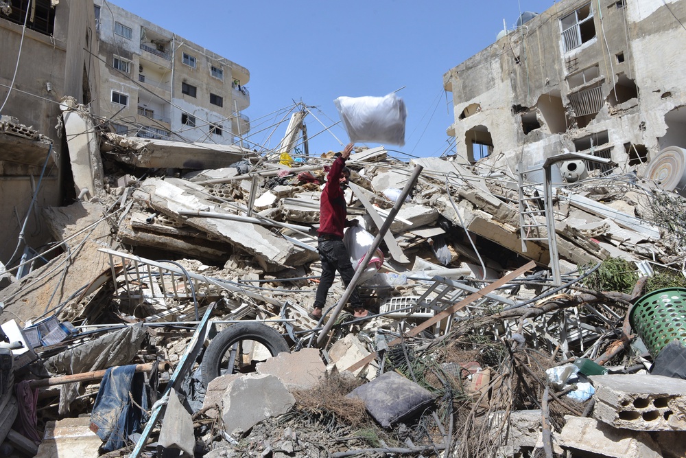 A man collects his family's belongings from the rubble of a building destroyed in an Israeli airstrike in the southern village of Maarakeh, Lebanon (AP)