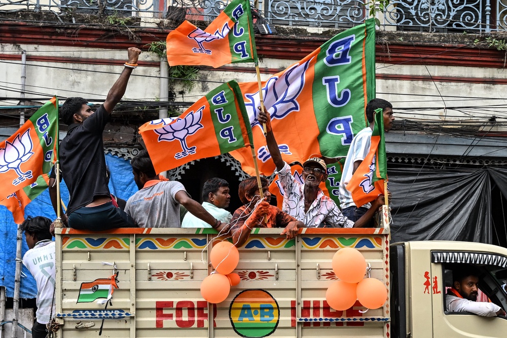 Supporters of the Bharatiya Janata Party (BJP) celebrate with the party flags as they return after attending the swearing-in ceremony of West Bengal's newly-elected Chief Minister Suvendu Adhikari (AFP/Getty)