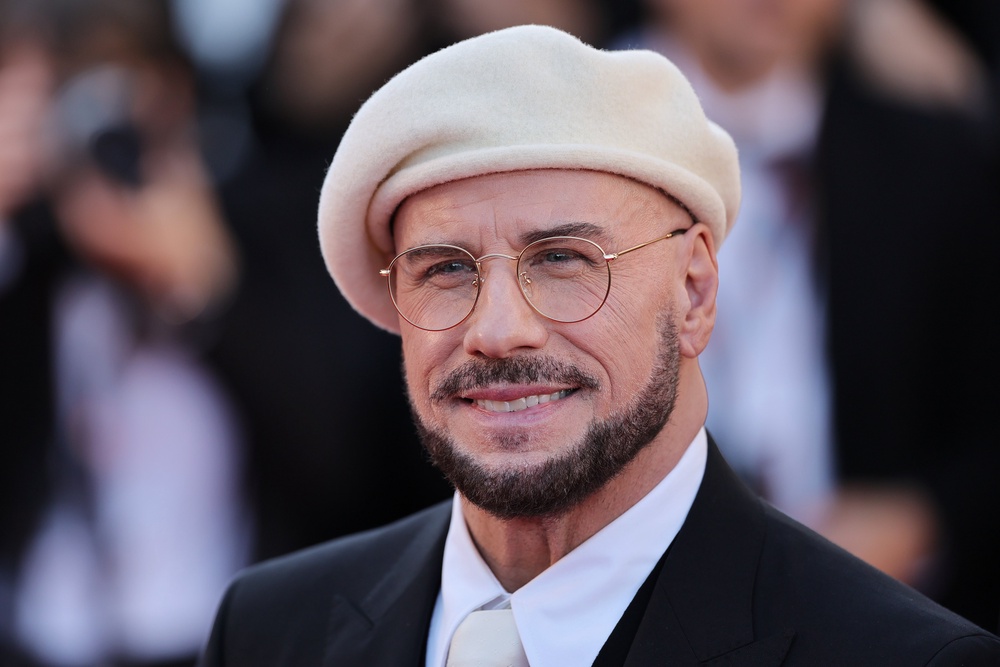 John Travolta wore a series of colored berets and round glasses to the 2026 Cannes Film Festival (Getty)