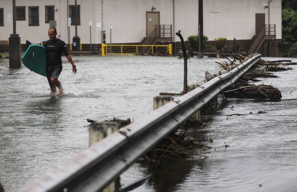 A resident carries his bodyboard through floodwaters after Tropical Storm Lane hit the Big Island in August 2018. Flooding and winds have devastated the Hawaiian islands in recent years (Getty)
