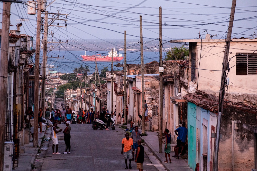 People walk trough a street, with an oil tanker ship in the background, in Matanzas, Cuba on March 30 (AFP/Getty)