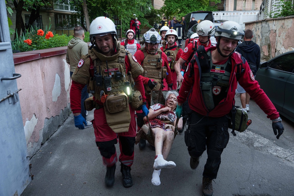 Red Cross volunteers carry an injured woman into an ambulance after a Russian strike on a residential neighborhood (AP)