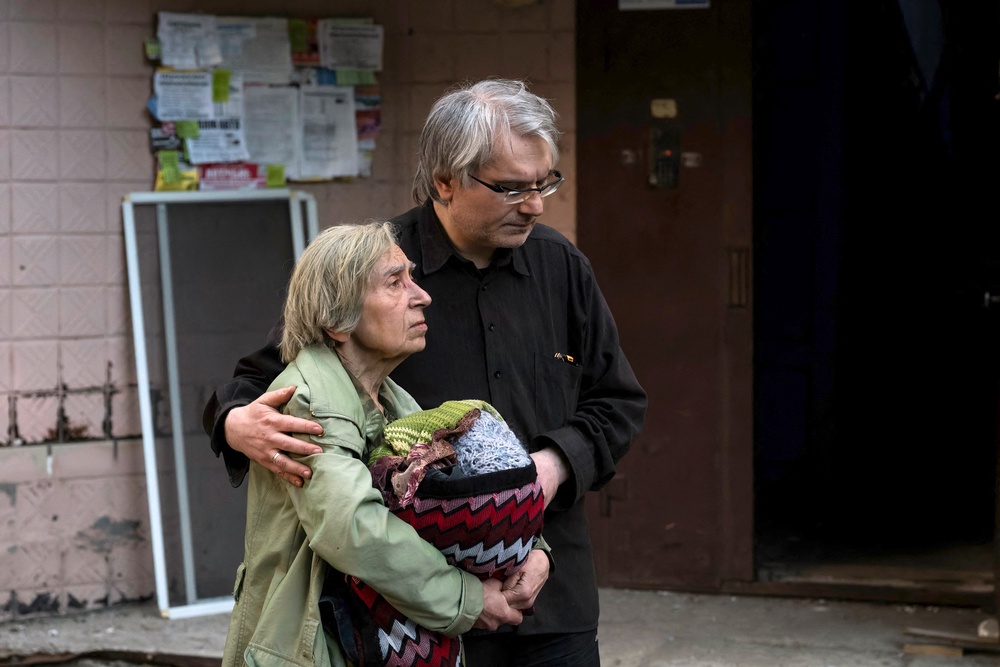 A man escorts a local resident during the evacuation of a damaged residential building following Russian strikes to the Ukrainian capital in Kyiv (AFP/Getty)
