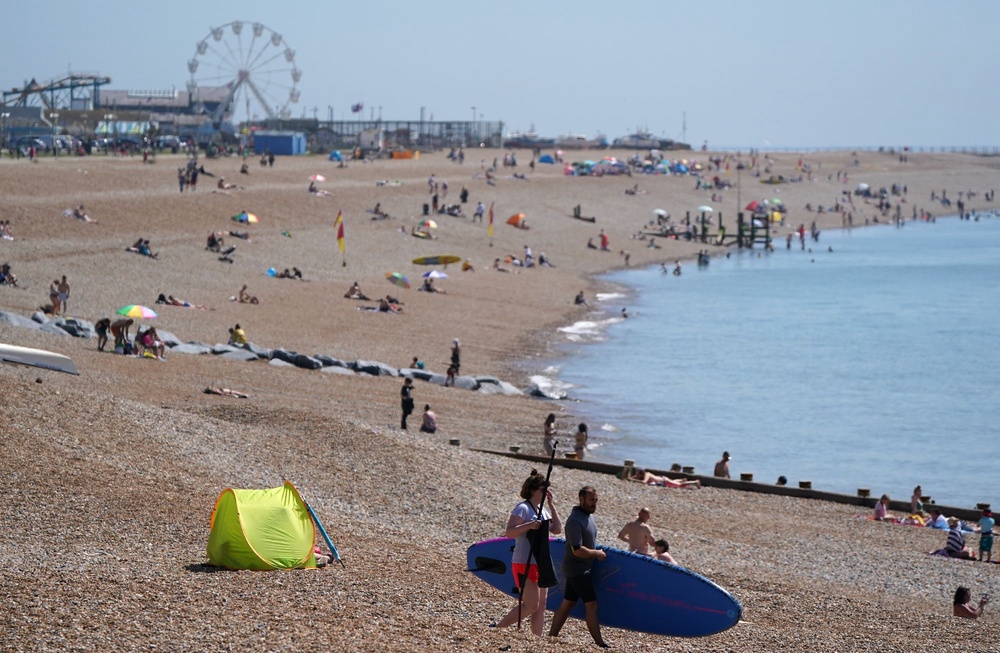 People enjoy the warm weather on Hastings beach in East Sussex in 2021 (PA)