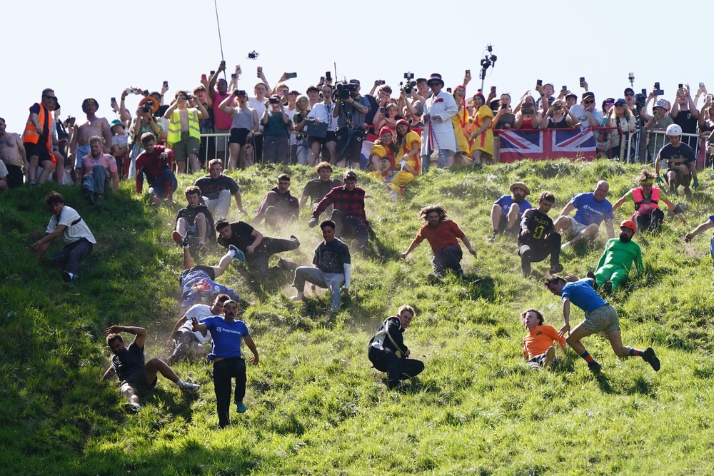 Participants take part in the first men’s downhill race during the annual cheese rolling at Cooper’s Hill in Brockworth, Gloucestershire (Jacob King/PA) (PA Wire)