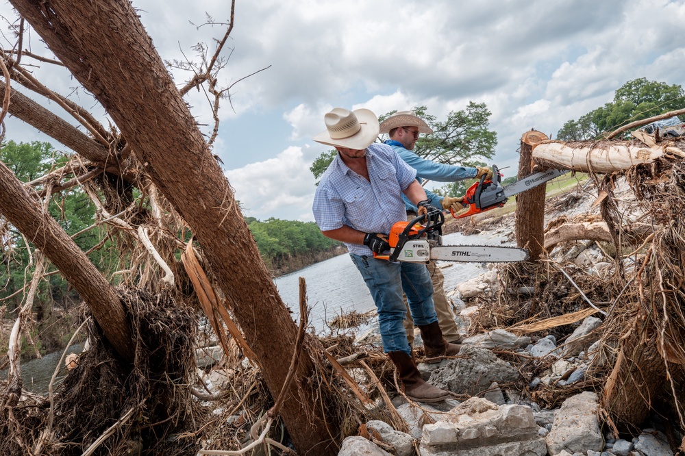 Volunteers Zak Coppinger and Bryan Bailey work to clear fallen trees in the wake of deadly flash floods in Hunt, Texas, last July. More flash floods are forecast in the area this summer (Getty)