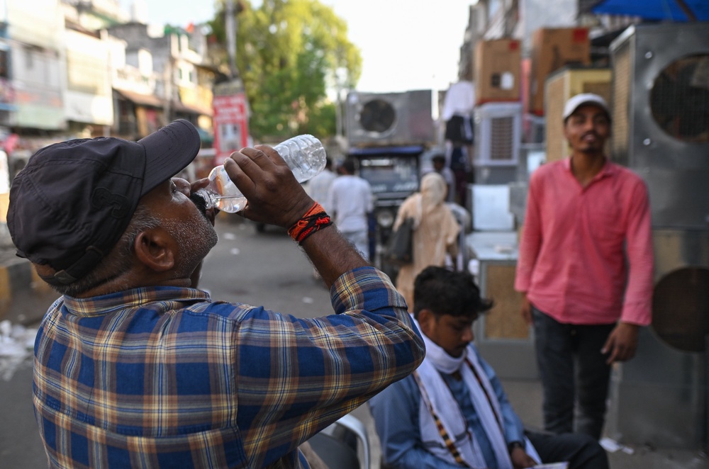 A man drinks water at a market selling air coolers and cooling appliances during hot weather conditions (Getty)