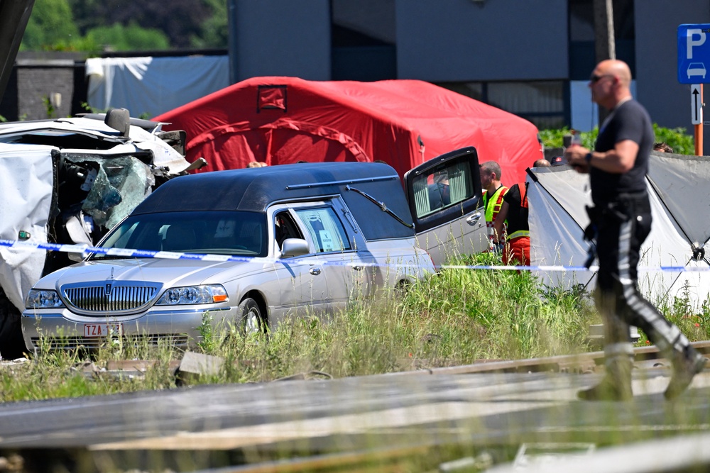 A hearse is parked next to the crashed bus at the site of an accident after a train crashed into a school bus, at the railway crossing Vierhuizen in Buggenhout (AFP/Getty)