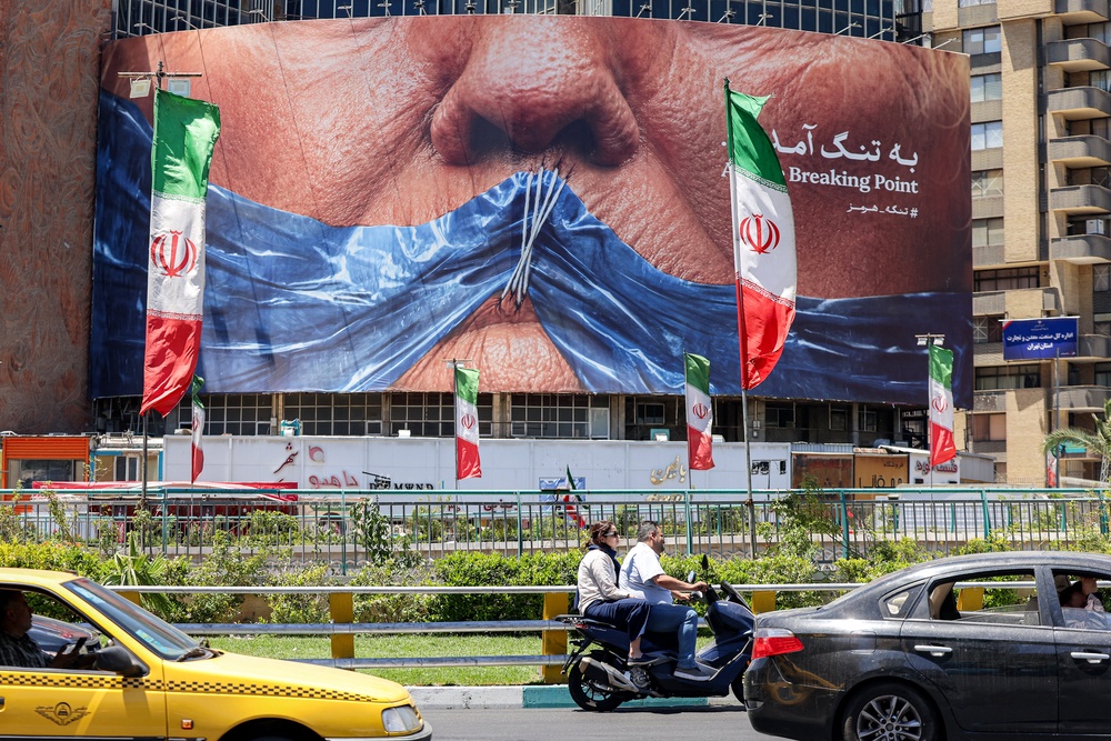 Motorists drive past a billboard featuring US president Donald Trump and the Strait of Hormuz in Valiasr Square, Tehran on 26 May (AFP/Getty)