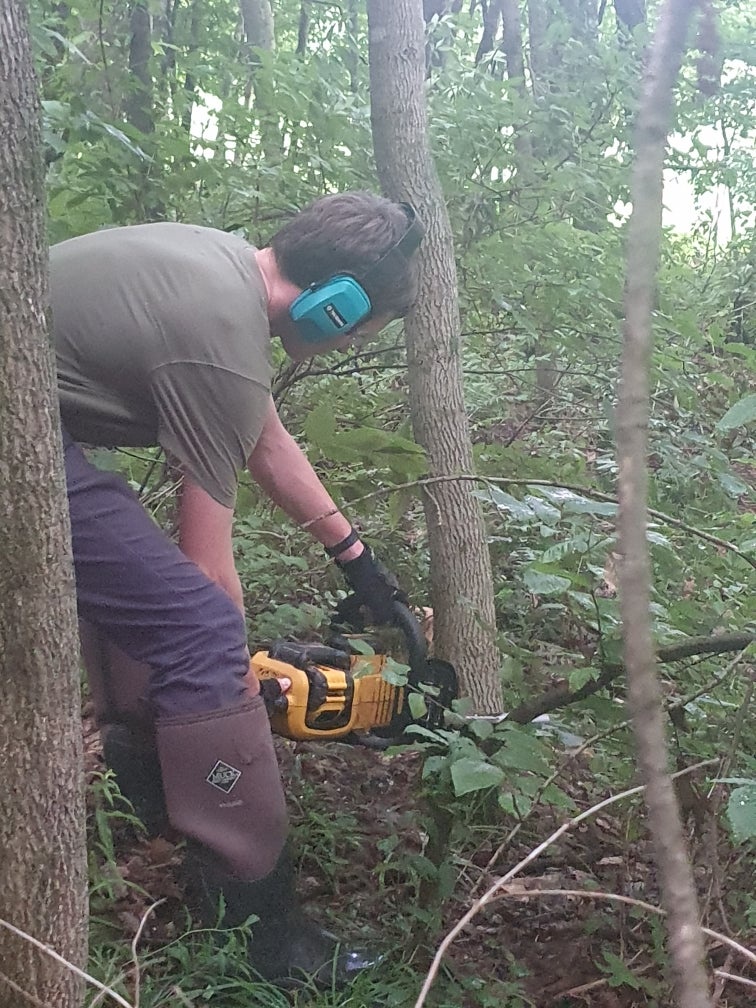 Derrendinger said it is ‘safer to give my kids a chainsaw than access to social media.’ Her teenage son uses the power tool to cut wood (pictured) for the small maple syrup operation he runs with his siblings in rural Vermont (Laura Derrendinger)