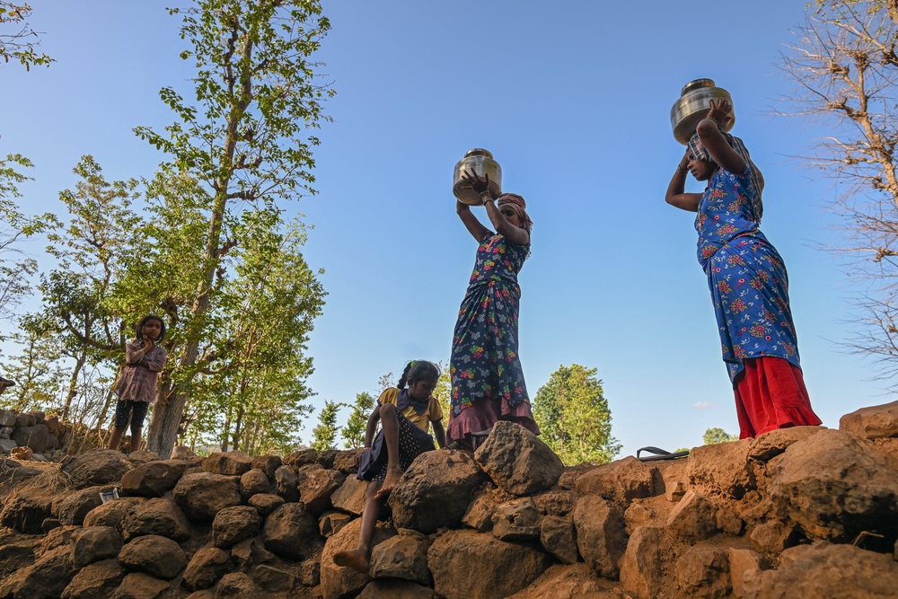 Women carry containers after collecting water from the stagnant and polluted remains of a partially dried well in a drought affected village (Getty)