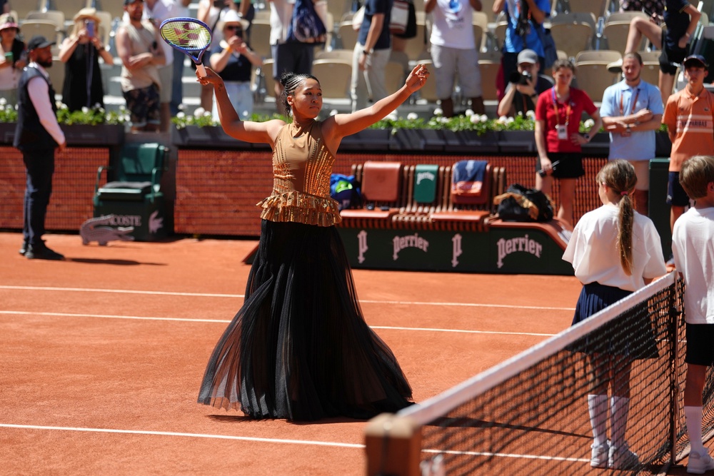 Noami Osaka shed her bodice and long pleated skirt to reveal the gold dress underneath (AP)