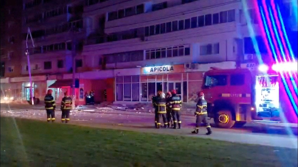 Firefighters work near a building, which, according to a Facebook post by Romanian radio station Pro Lider FM, was hit by a drone, close to the border with Ukraine, in Galati, Romania (Reuters)