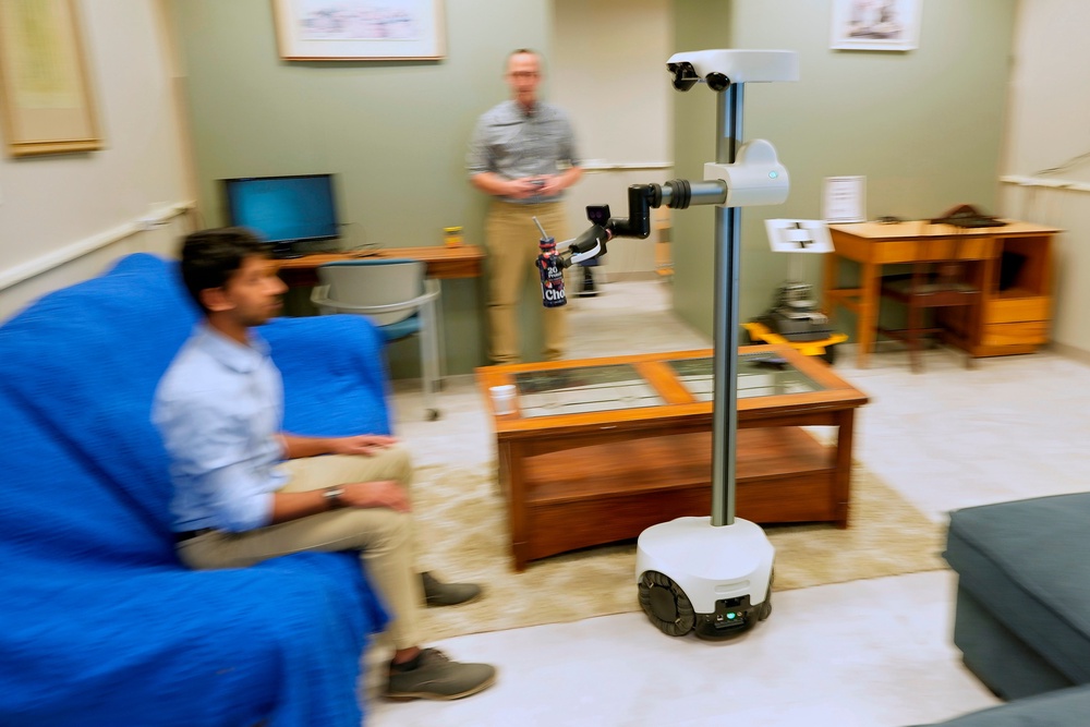 A robot operated by a robotics engineer, rear, brings a drink to colleague during a demonstration at the University of New Hampshire (Copyright 2026 The Associated Press. All rights reserved)