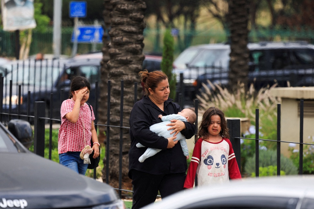 A woman carrying a child walks along a road as people flee the southern suburbs of Beirut, after Israeli Prime Minister Benjamin Netanyahu ordered the military to attack targets in the suburbs, Lebanon, June 1, 2026. (Reuters)