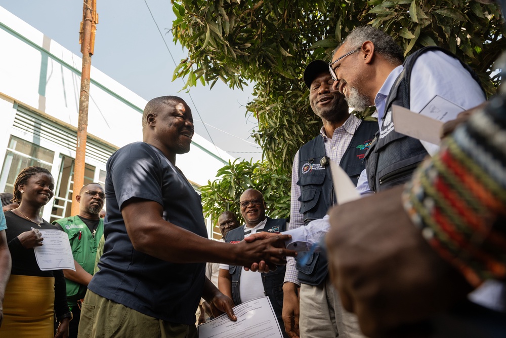 Director General of the World Health Organization (WHO), Tedros Adhanom Ghebreyesus, right, shakes hands with Ezo Étienne (AP)