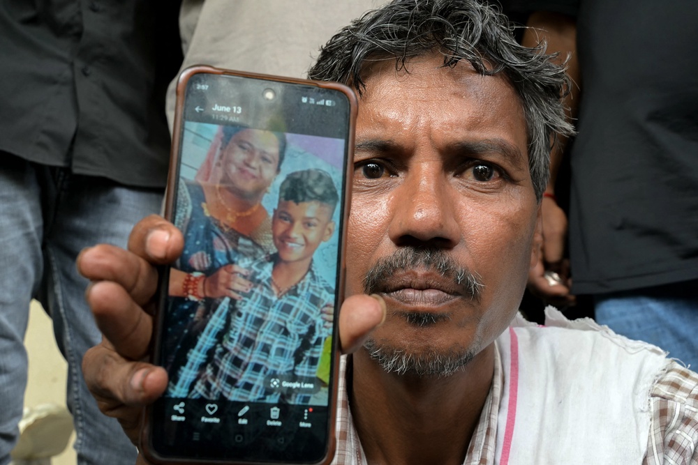 Suresh Patni shows a picture of his wife and son as he waits outside a hospital in Ahmedabad on 15 June 2025 (AFP/Getty)