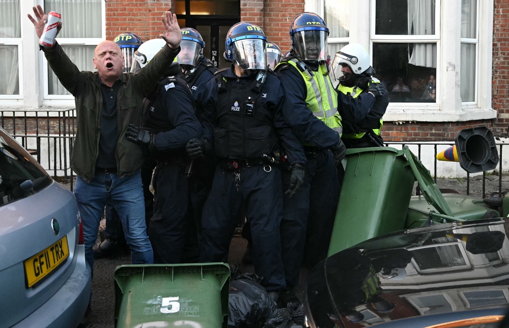A person attempts to calm the crowd as Police officers are attacked by demonstrators near Portswood Police Station, following a protest march in Southampton (AFP/Getty)