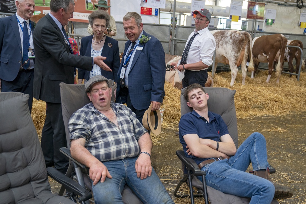 A couple of farmers sleep as the Princess Royal tours the cattle stalls in the Highland Hall during a visit to the Royal Highland Show at the Royal Highland Centre in Ingliston, Edinburgh (Jane Barlow/PA) (PA Archive)